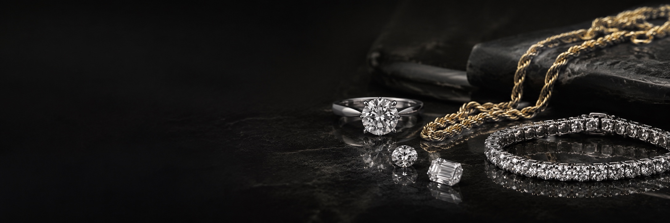 A diamond solitaire ring, gold rope chains, loose diamonds and a diamond tennis bracelet on dark slate