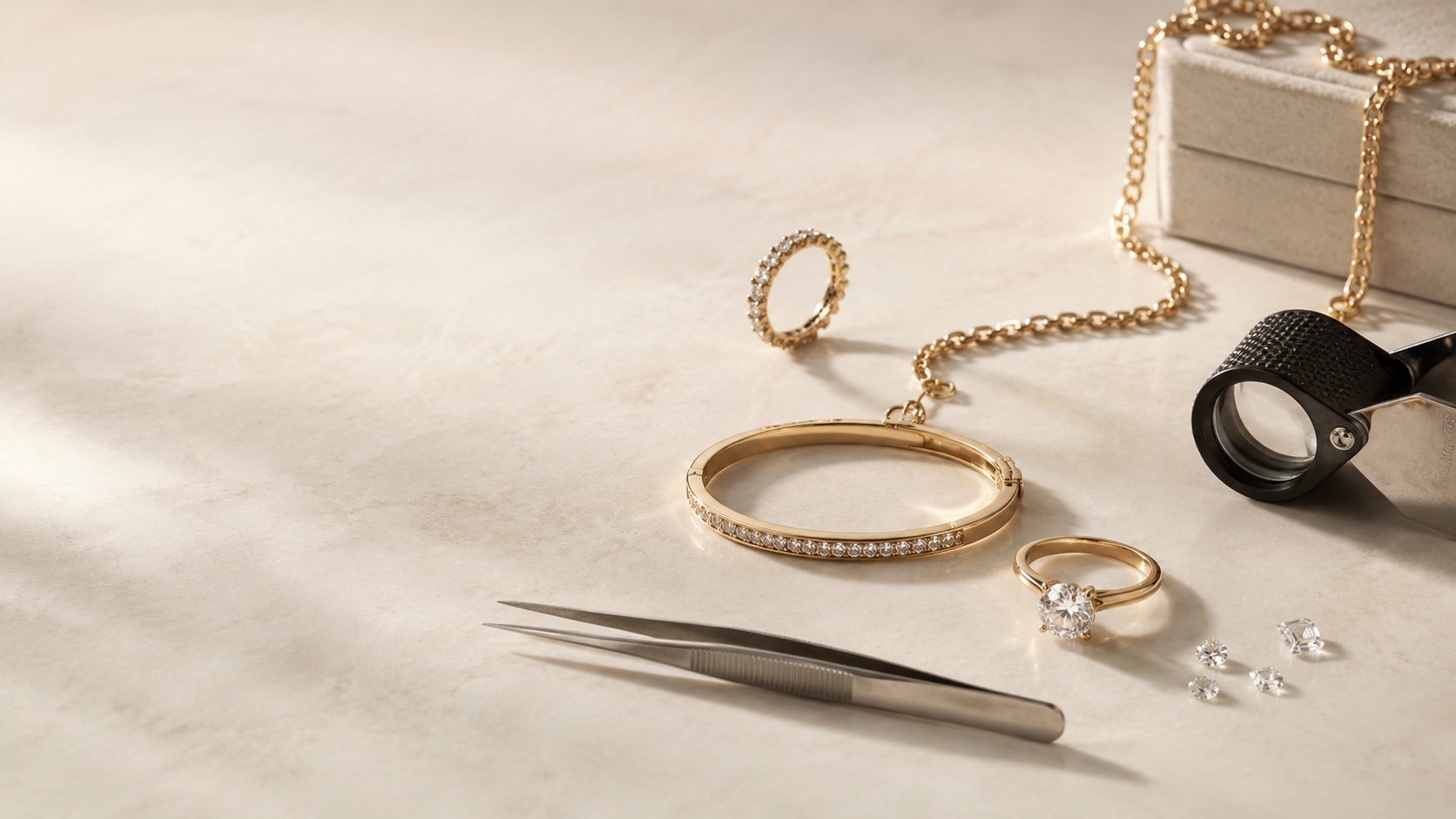 A gold diamond eternity ring, a diamond-set gold bangle, a gold solitaire ring, loose diamonds, tweezers and a jeweller's loupe on pale marble